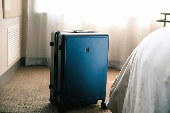 Une valise à côté d'un lit.